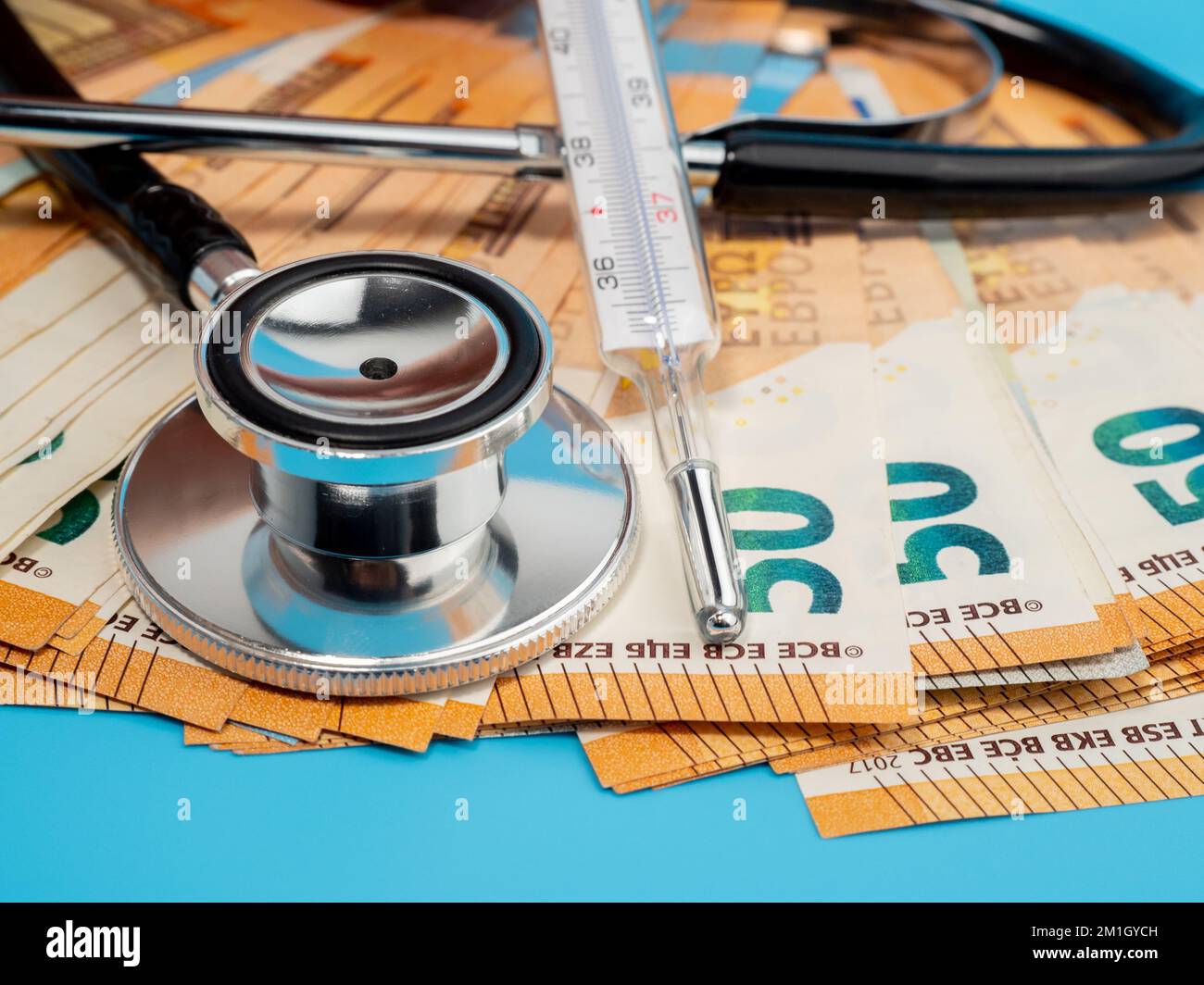 Medizinisches Stethoskop, Thermometer und Banknoten auf blauem Hintergrund. Nahaufnahme. Stockfoto