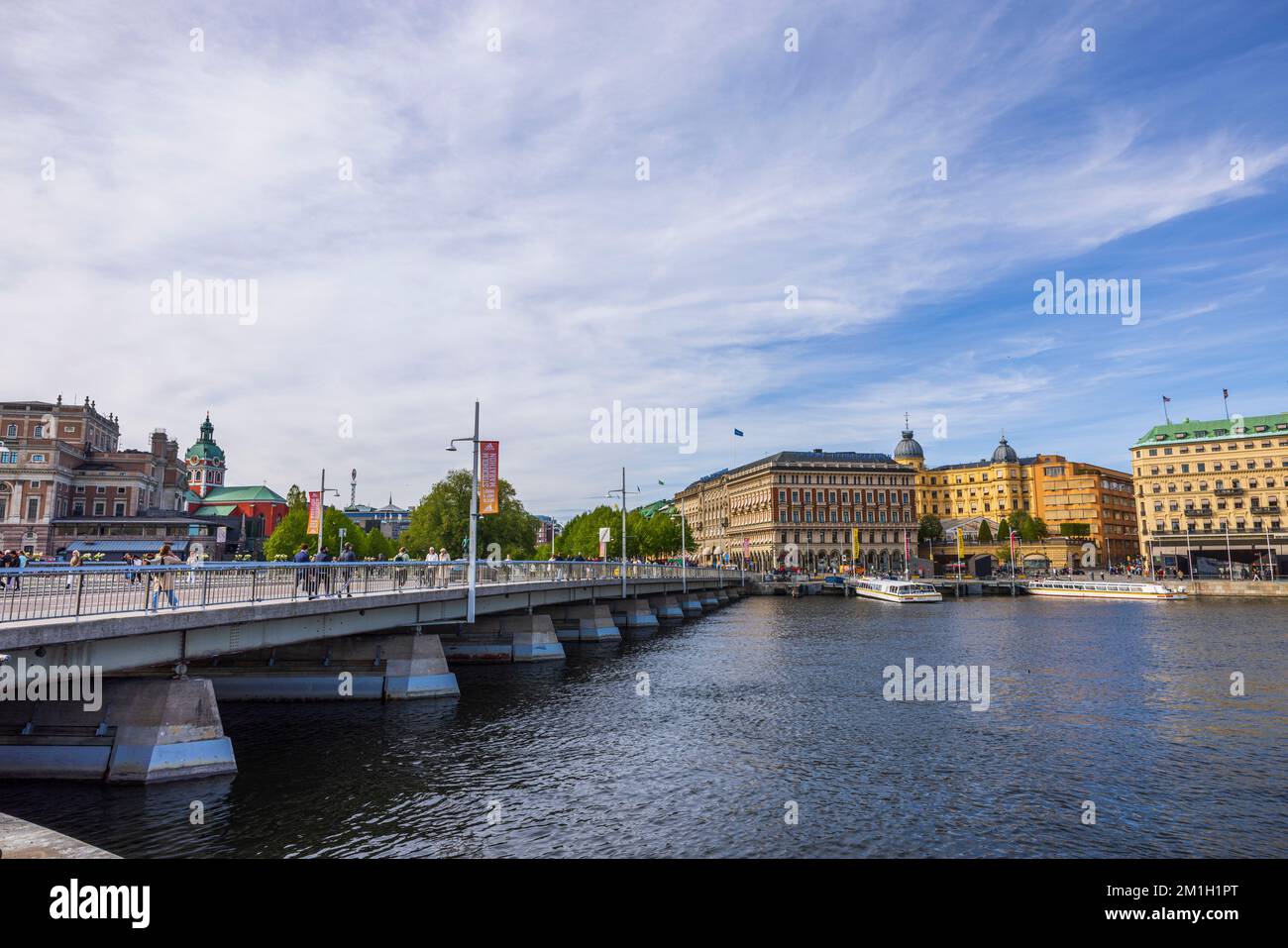 Wunderschöner Blick auf die Stadtlandschaft von Stockholm. Menschen, die auf einer Brücke über den Fluss laufen. Schweden. Stockholm. 05.18.2022. Stockfoto