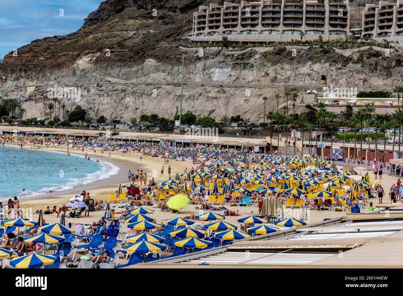 Der lebendige Strand und die atemberaubende Landschaft von Playa de Amadores auf Gran Canaria werden mit einem Farbtupfer zum Leben erweckt. Stockfoto