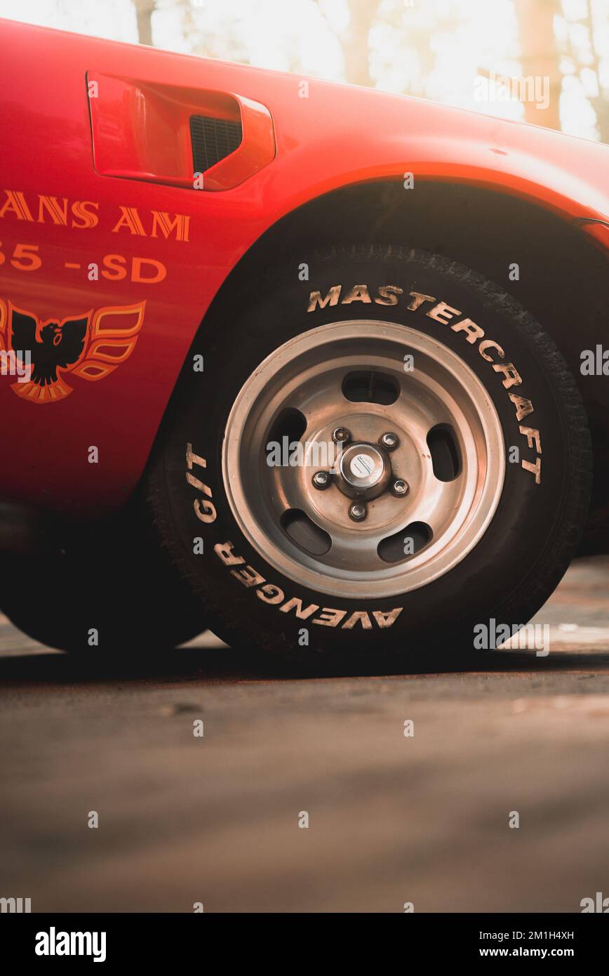Eine vertikale Aufnahme des Vorderrads des amerikanischen roten Pontiac Firebird mit dem Text „Mastercraft Avenger git“ Stockfoto