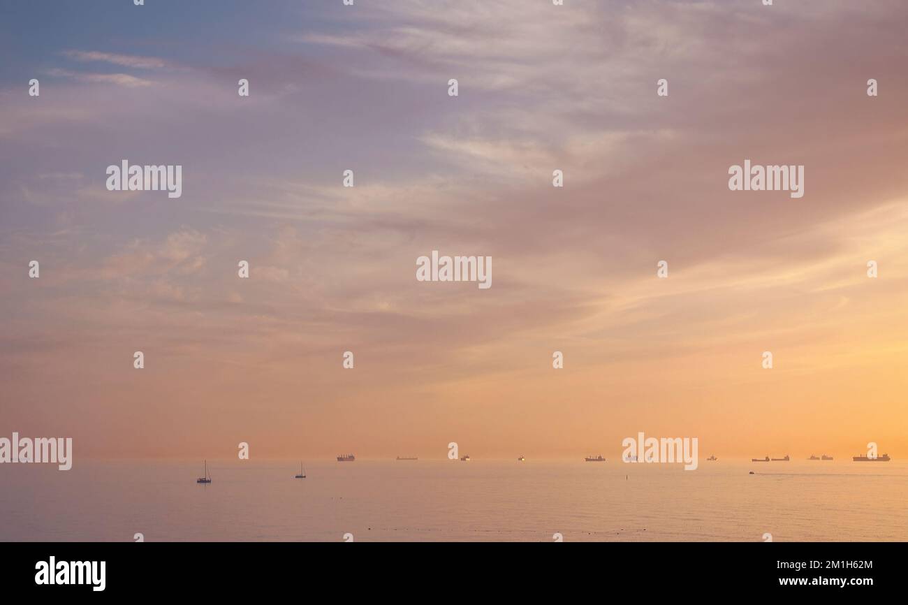 Majestätischer Sonnenuntergang über dem Wasser, viele verschiedene Schiffe und Yachten in einem Meer Stockfoto