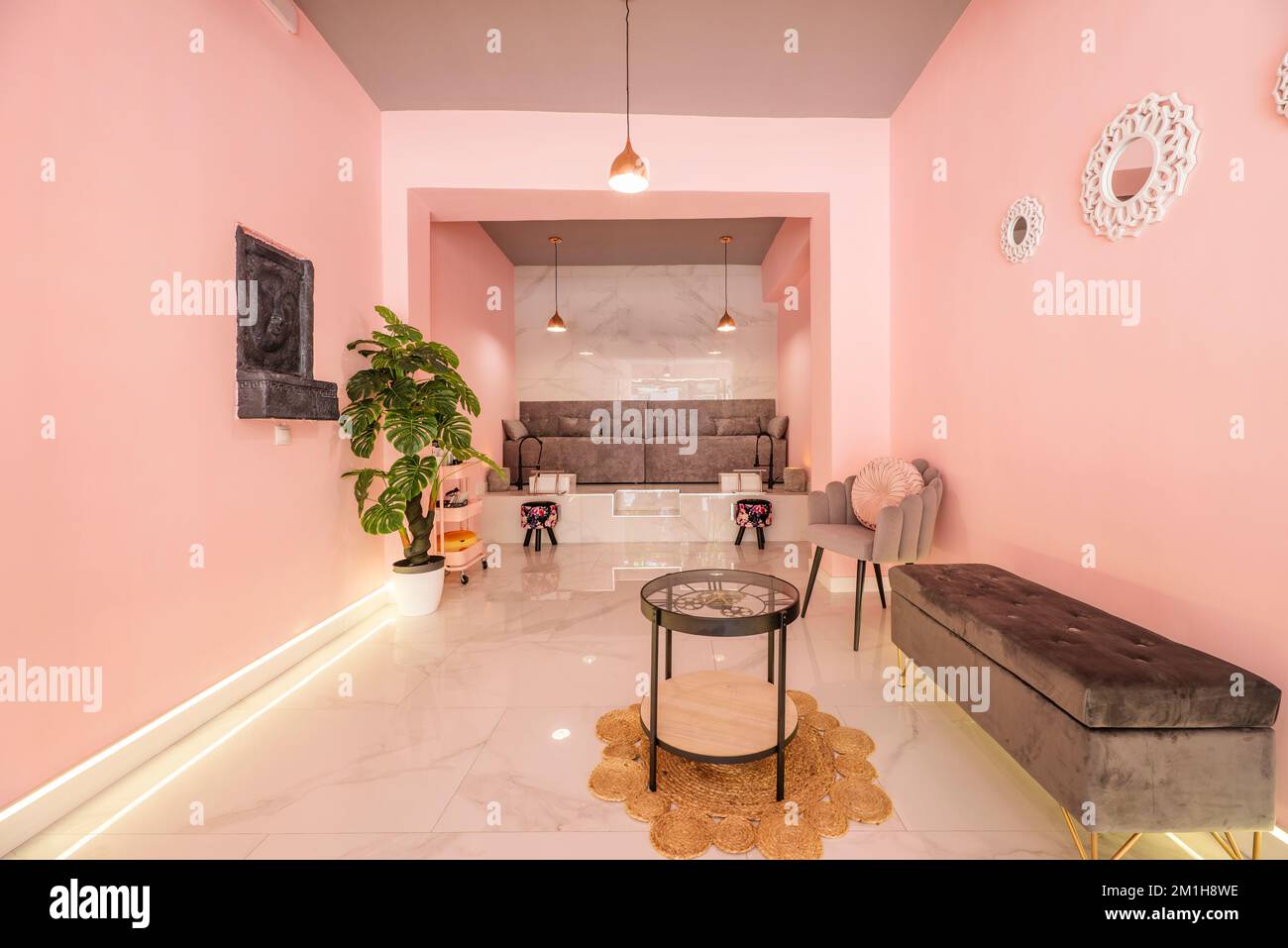Zimmer eines Schönheitssalons mit rosafarbenen Wänden und grauen Samtsitzen Stockfoto