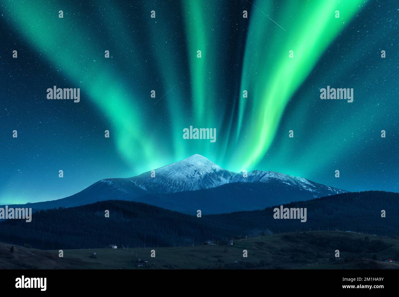 Aurora borealis über dem schneebedeckten Berggipfel Stockfoto