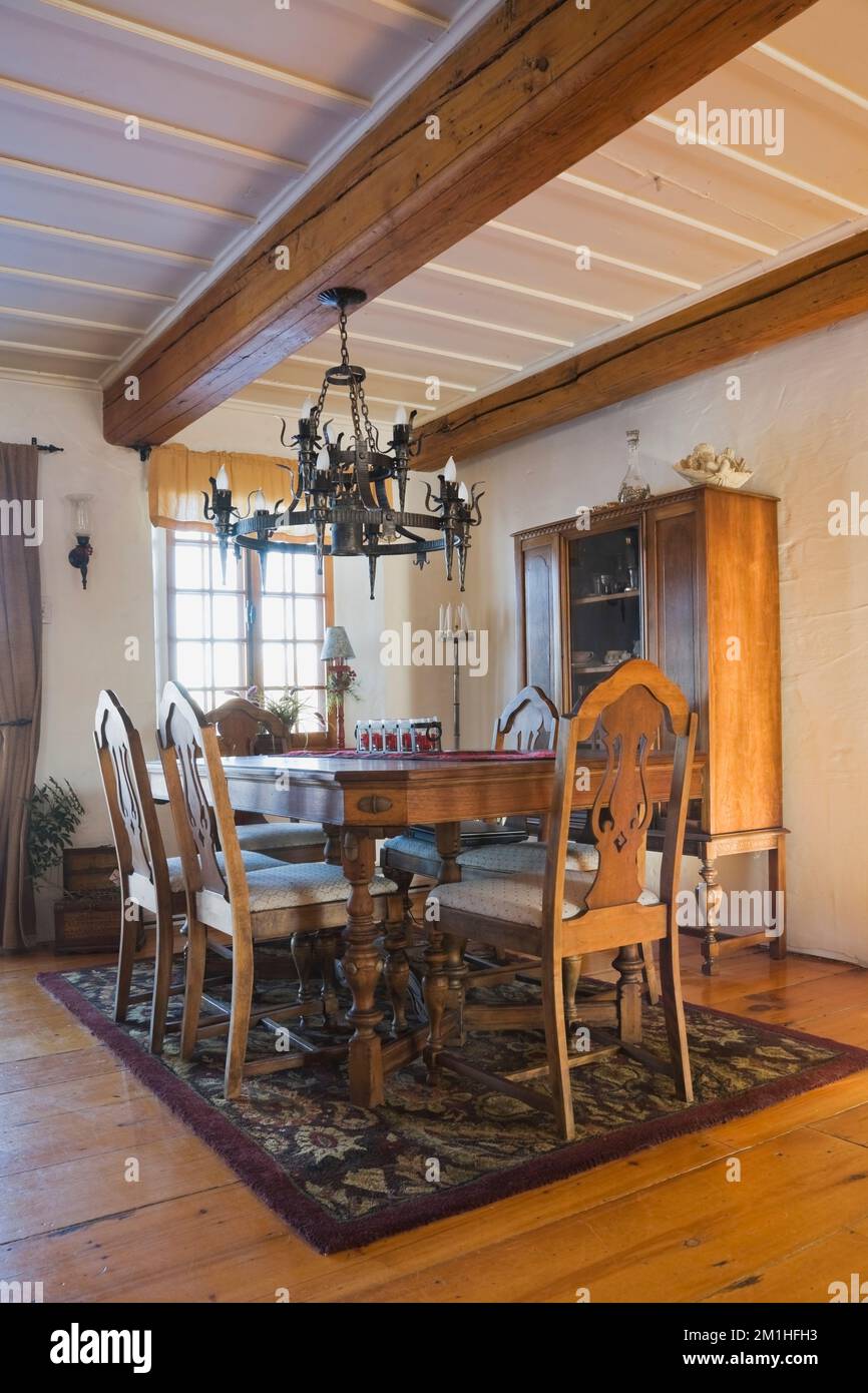 Antiker Holztisch und Stühle mit hohen Rückenlehnen mit geschnitzten Motiven im Speisesaal im alten Blockhaus im Landhausstil aus den 1800er Jahren. Stockfoto