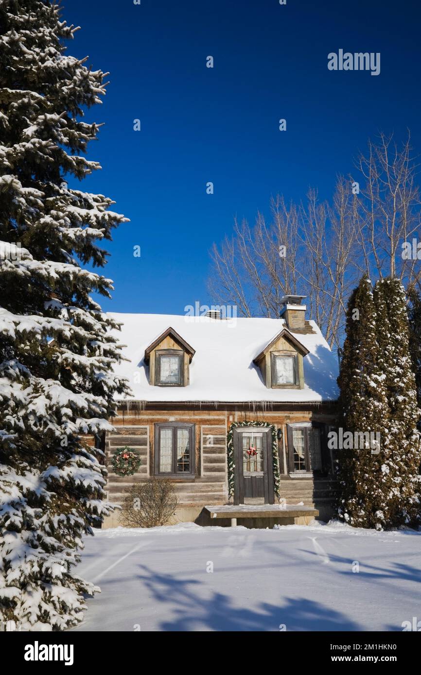 1982 erbaute Nachbildung des 1800er Canadiana zweistöckigen Blockhauses mit Weihnachtsdekorationen im Winter. Stockfoto