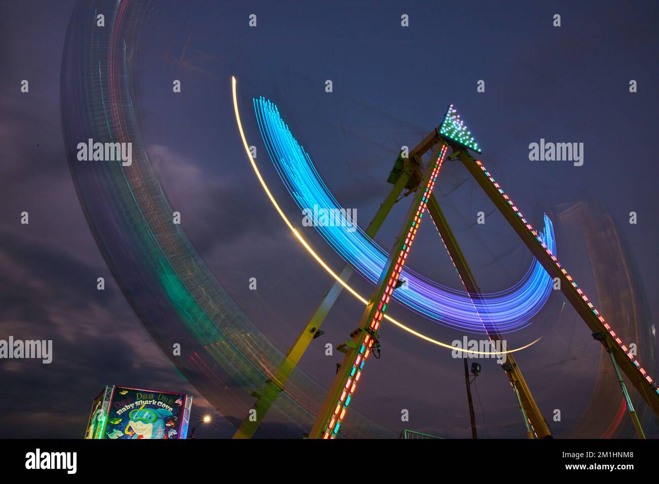 Karnevalsfahrt in der Abenddämmerung mit verschwommenen Lichtern auf dem Jahrmarkt Stockfoto