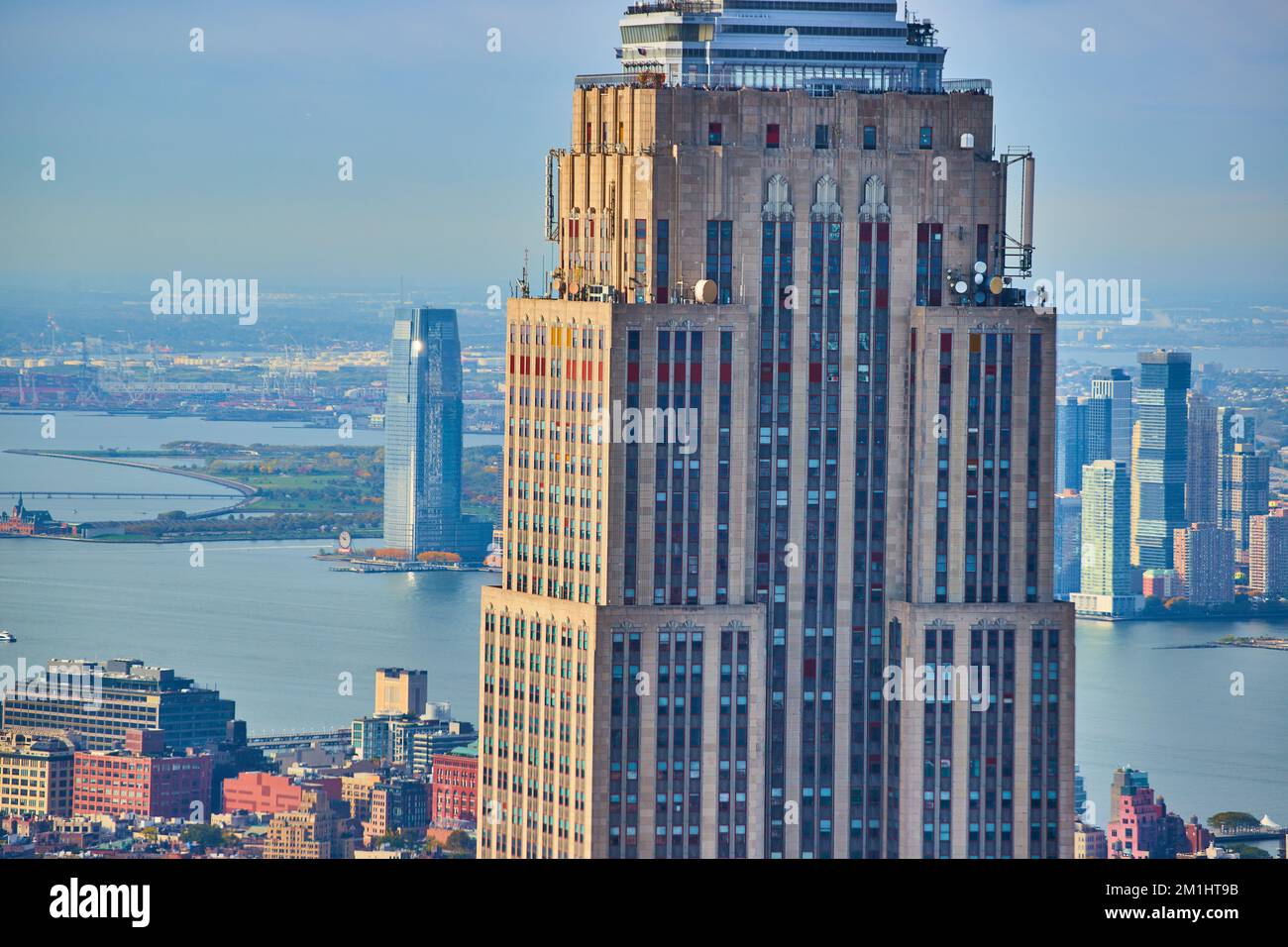 Detail-Zoom hoch oben auf einem Teil des Empire State Building mit Stadt und Fluss dahinter Stockfoto