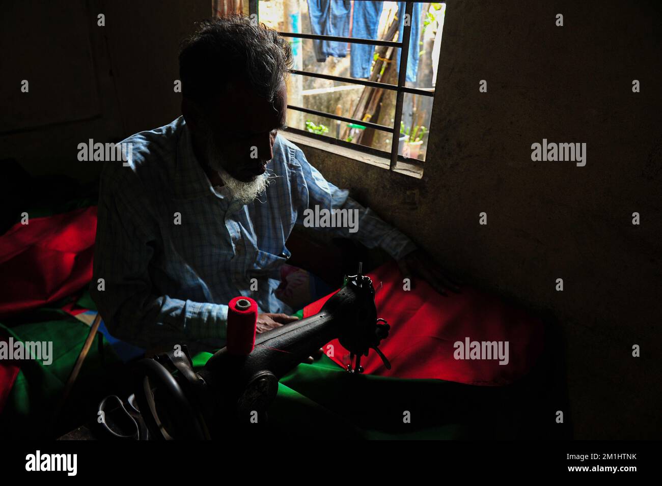 12. Dezember 2022 Sylhet-Bangladesch: Ein 55-jähriger Schneider Kaosar Khan von Sylhets Loharpara, der die Nationalflagge von Bangladesch näht. Etwa die Hälfte der Tausenden von Nationalflaggen, die er näht und die das ganze Jahr über im Dezember verkauft werden. Bangladesch hat im bewaffneten Befreiungskrieg vor 51 Jahren in diesem Dezember 1971 den Sieg errungen . Im Austausch für 3 Millionen Leben und Ehre von 200.000 Frauen in neun Monaten Krieg kam dieser Moment am 16. Dezember. Bangladesch feiert diese Errungenschaft noch immer mit der gebührenden würde. Am 12. Dezember 2022 in Sylhet, Bangladesch (Foto: MD Rafayat Haque Khan/Eyepix Group) Stockfoto