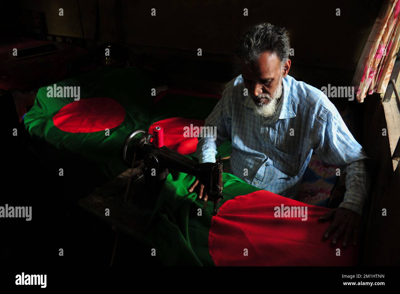 12. Dezember 2022 Sylhet-Bangladesch: Ein 55-jähriger Schneider Kaosar Khan von Sylhets Loharpara, der die Nationalflagge von Bangladesch näht. Etwa die Hälfte der Tausenden von Nationalflaggen, die er näht und die das ganze Jahr über im Dezember verkauft werden. Bangladesch hat im bewaffneten Befreiungskrieg vor 51 Jahren in diesem Dezember 1971 den Sieg errungen . Im Austausch für 3 Millionen Leben und Ehre von 200.000 Frauen in neun Monaten Krieg kam dieser Moment am 16. Dezember. Bangladesch feiert diese Errungenschaft noch immer mit der gebührenden würde. Am 12. Dezember 2022 in Sylhet, Bangladesch (Foto: MD Rafayat Haque Khan/Eyepix Group) Stockfoto