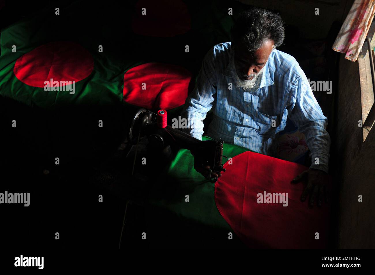 12. Dezember 2022 Sylhet-Bangladesch: Ein 55-jähriger Schneider Kaosar Khan von Sylhets Loharpara, der die Nationalflagge von Bangladesch näht. Etwa die Hälfte der Tausenden von Nationalflaggen, die er näht und die das ganze Jahr über im Dezember verkauft werden. Bangladesch hat im bewaffneten Befreiungskrieg vor 51 Jahren in diesem Dezember 1971 den Sieg errungen . Im Austausch für 3 Millionen Leben und Ehre von 200.000 Frauen in neun Monaten Krieg kam dieser Moment am 16. Dezember. Bangladesch feiert diese Errungenschaft noch immer mit der gebührenden würde. Am 12. Dezember 2022 in Sylhet, Bangladesch (Foto: MD Rafayat Haque Khan/Eyepix Group) Stockfoto