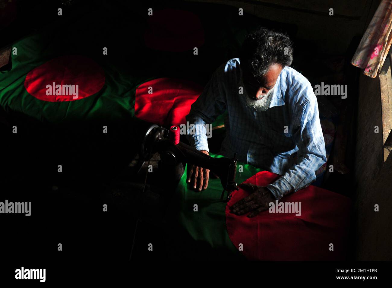 12. Dezember 2022 Sylhet-Bangladesch: Ein 55-jähriger Schneider Kaosar Khan von Sylhets Loharpara, der die Nationalflagge von Bangladesch näht. Etwa die Hälfte der Tausenden von Nationalflaggen, die er näht und die das ganze Jahr über im Dezember verkauft werden. Bangladesch hat im bewaffneten Befreiungskrieg vor 51 Jahren in diesem Dezember 1971 den Sieg errungen . Im Austausch für 3 Millionen Leben und Ehre von 200.000 Frauen in neun Monaten Krieg kam dieser Moment am 16. Dezember. Bangladesch feiert diese Errungenschaft noch immer mit der gebührenden würde. Am 12. Dezember 2022 in Sylhet, Bangladesch (Foto: MD Rafayat Haque Khan/Eyepix Group) Stockfoto