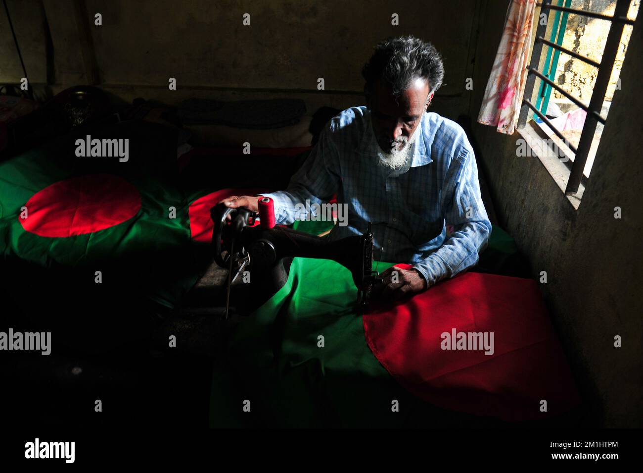 12. Dezember 2022 Sylhet-Bangladesch: Ein 55-jähriger Schneider Kaosar Khan von Sylhets Loharpara, der die Nationalflagge von Bangladesch näht. Etwa die Hälfte der Tausenden von Nationalflaggen, die er näht und die das ganze Jahr über im Dezember verkauft werden. Bangladesch hat im bewaffneten Befreiungskrieg vor 51 Jahren in diesem Dezember 1971 den Sieg errungen . Im Austausch für 3 Millionen Leben und Ehre von 200.000 Frauen in neun Monaten Krieg kam dieser Moment am 16. Dezember. Bangladesch feiert diese Errungenschaft noch immer mit der gebührenden würde. Am 12. Dezember 2022 in Sylhet, Bangladesch (Foto: MD Rafayat Haque Khan/Eyepix Group) Stockfoto