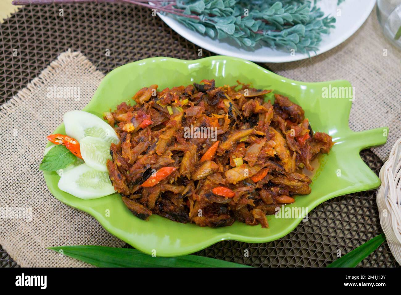 Pampis Tongkol/Cakalang, Manados traditionelles Fischgericht mit scharfem Fisch, serviert auf grünem Teller Stockfoto