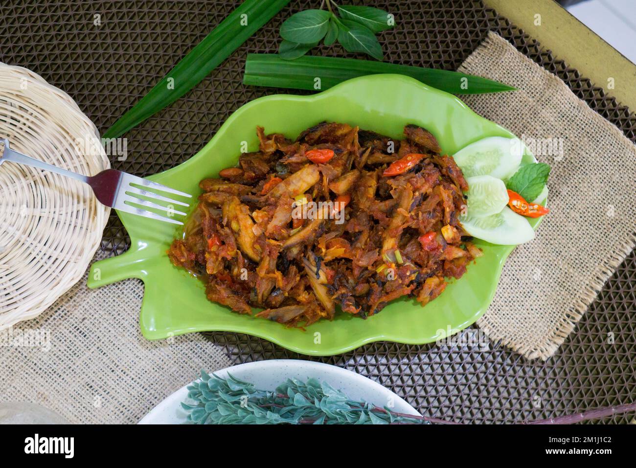 Pampis Tongkol/Cakalang, Manados traditionelles Fischgericht mit scharfem Fisch, serviert auf grünem Teller Stockfoto