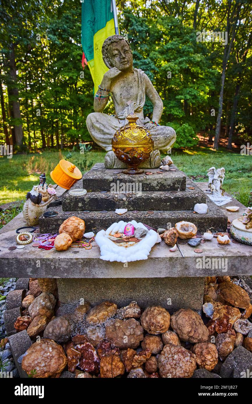 Geodes gespendet an kleine steinerne tibetische mongolische buddhistische Statue im Wald Stockfoto