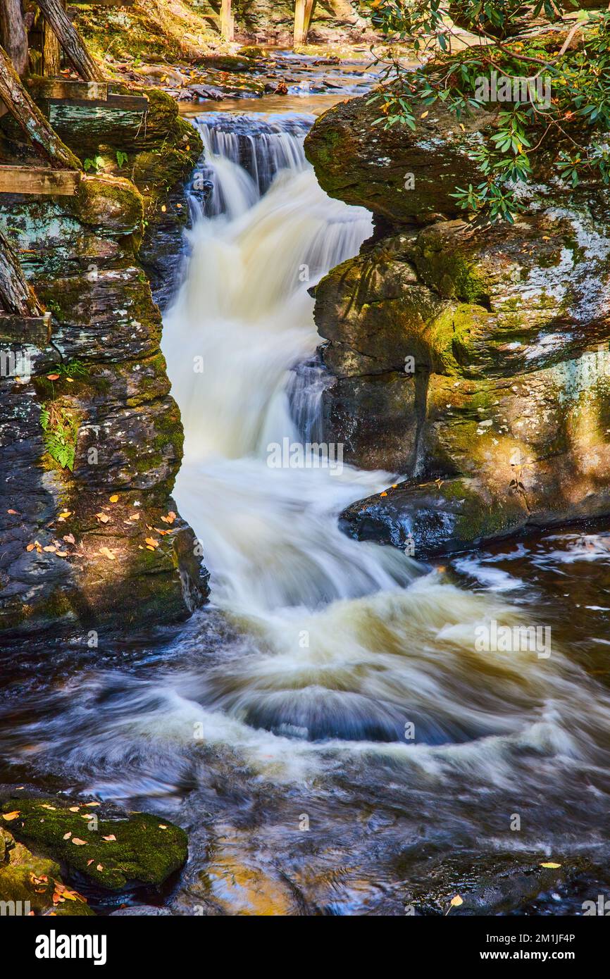 Detaildarstellung eines kleinen Wasserfalls durch mit Flechten und Moos bedeckte Felsen Stockfoto