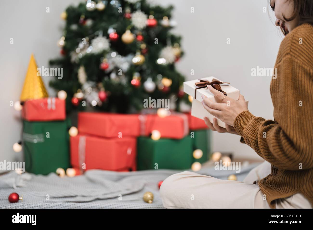 Nahhand einer asiatischen Frau präsentiert Weihnachtsgeschenk in offener Schachtel zu Hause. Speicherplatz kopieren Stockfoto