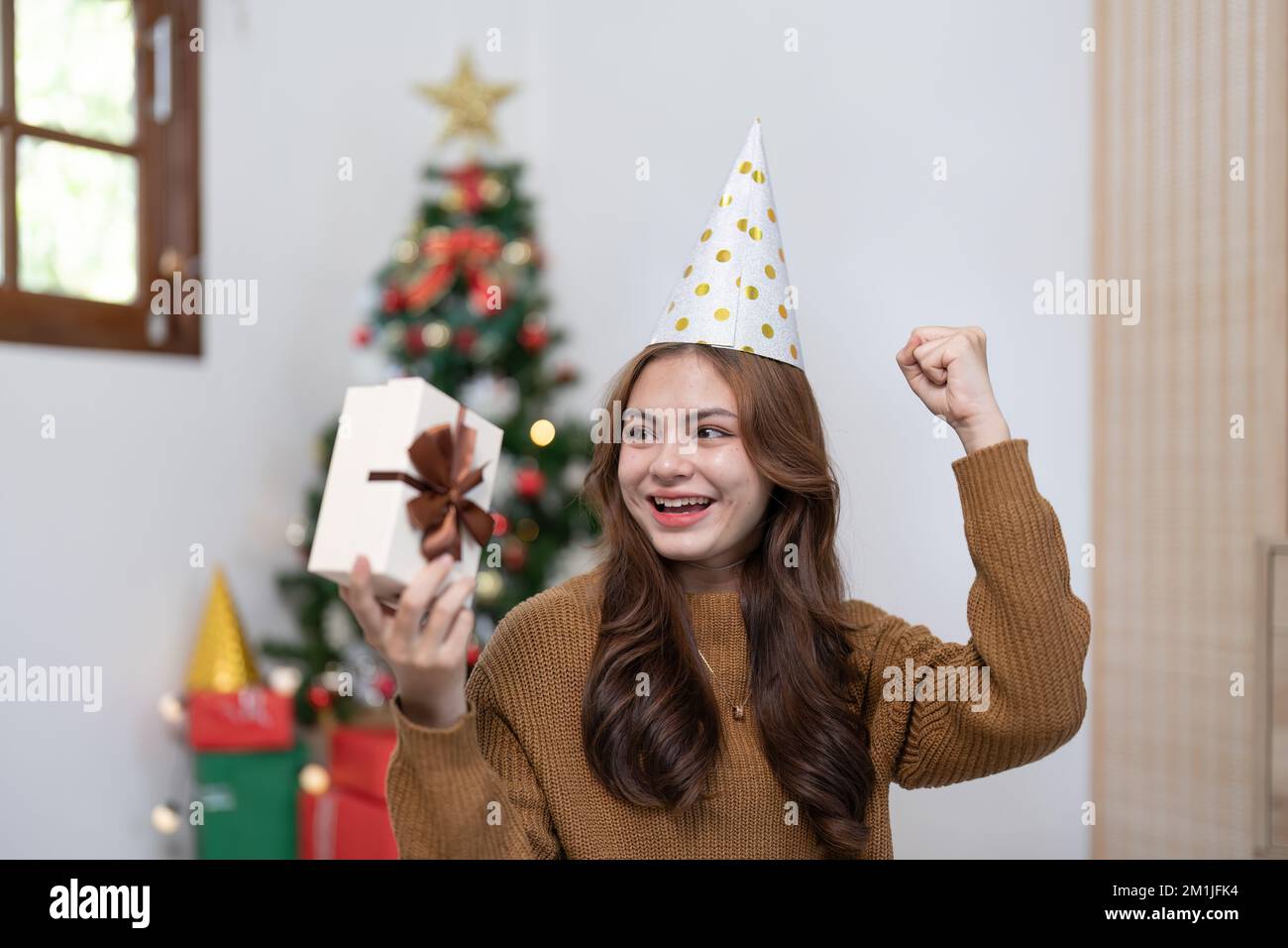 Porträt einer lächelnden asiatischen Frau mit Weihnachtsgeschenk zu Hause Stockfoto