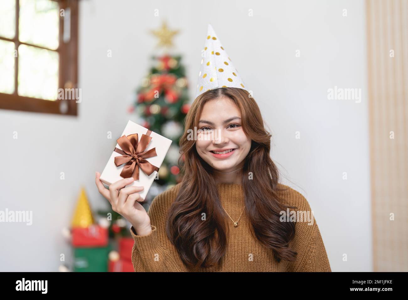 Porträt einer lächelnden asiatischen Frau mit Weihnachtsgeschenk zu Hause Stockfoto