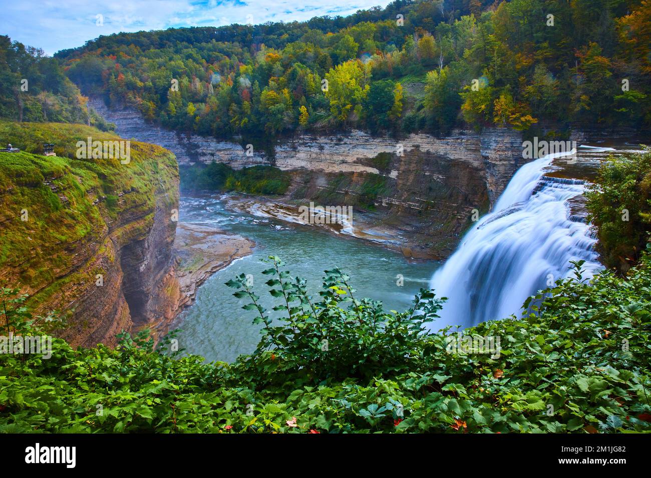 Wasserfall von der Seite, der in einen riesigen Canyon mit Klippen und Wäldern im frühen Herbst strömt Stockfoto