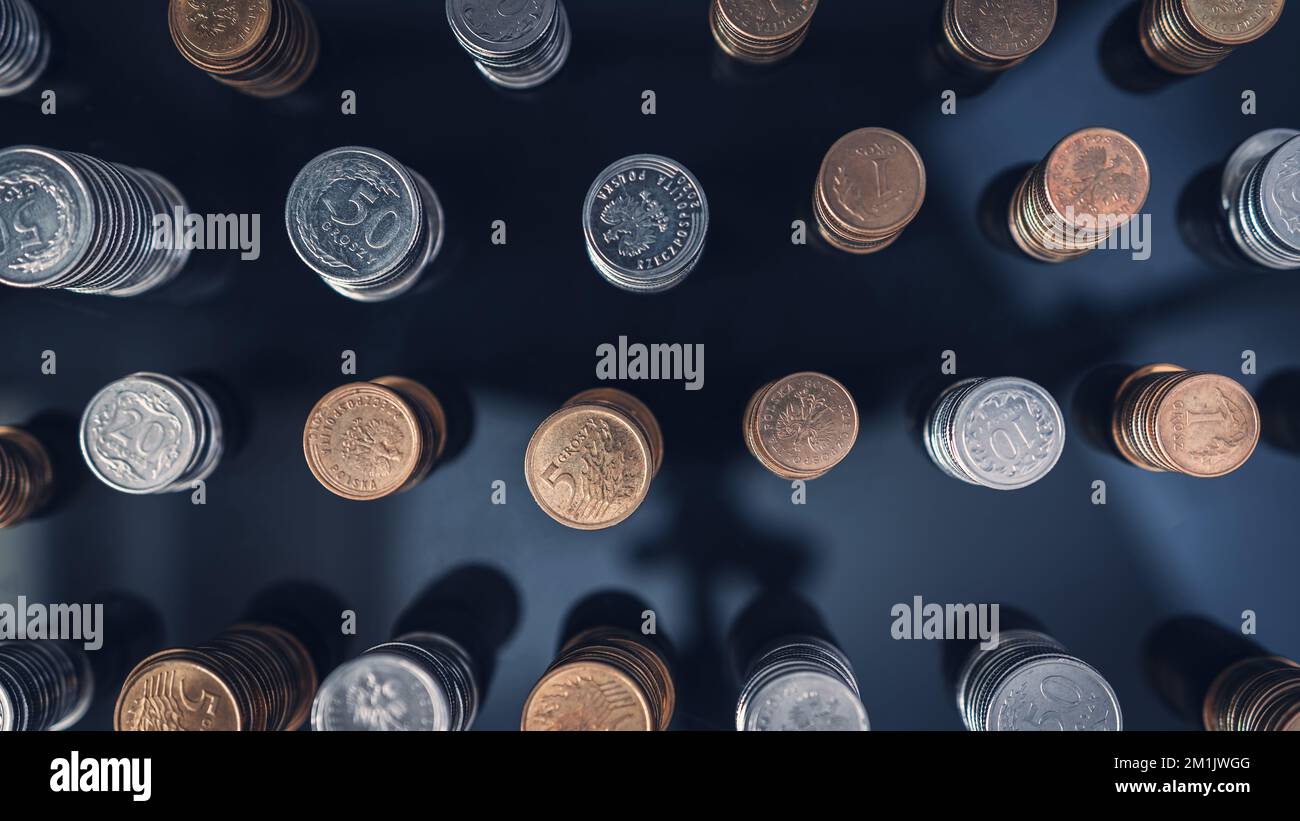 Stapel von Münzen (Polish Zloty, Grosze, PLN) auf einer schwarzen, reflektierenden Oberfläche, von oben gesehen. Inflation verschlingt unsere Ersparnisse. Schwierige Wirtschaftslage Stockfoto