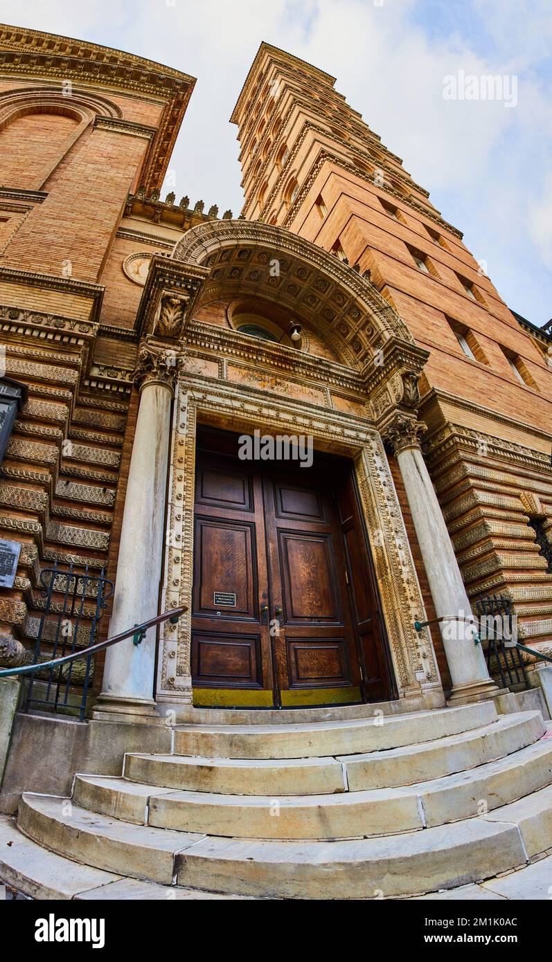 Eingang zur alten Kirche mit großen braunen Türen und einem majestätischen hellbraunen Ziegelturm Stockfoto