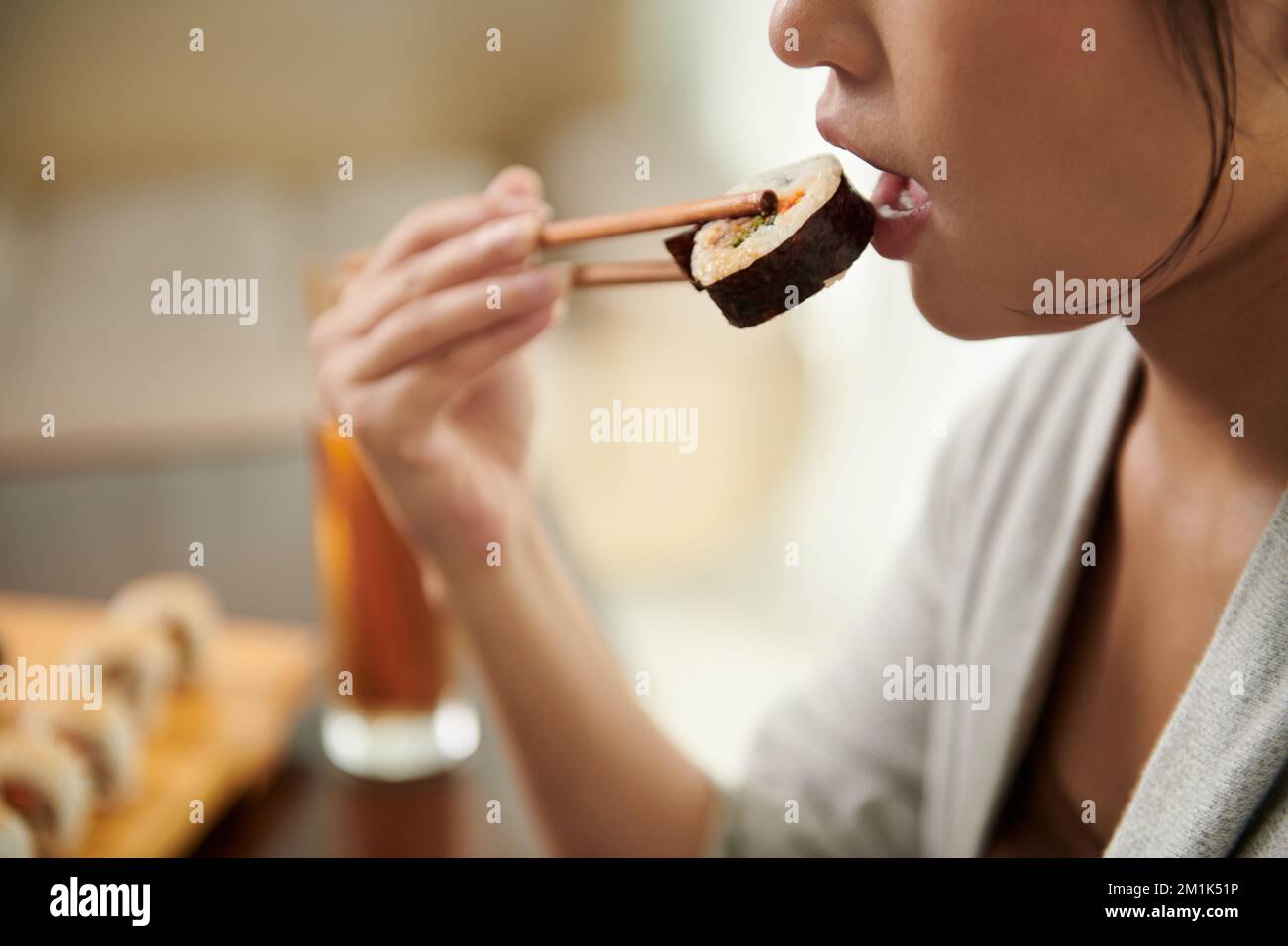 Junge Frau, die köstliches Sushi im Restaurant isst Stockfoto