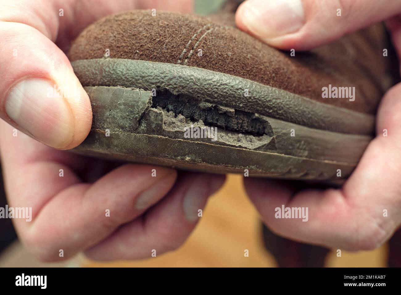 Nahaufnahme einer Person, die einen Schuh mit gerissener Sohle hält Stockfoto