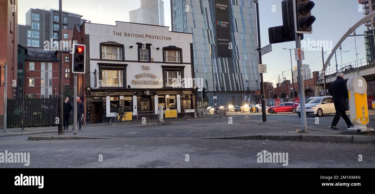 Eine Panoramafassade mit Straßenautos vom alten Pub Briton's Protection Manchester Stockfoto