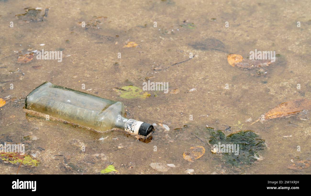 Glasflasche im Wasser, Verschmutzung von Wasserkörpern, Müll im Meer und Fluss Stockfoto
