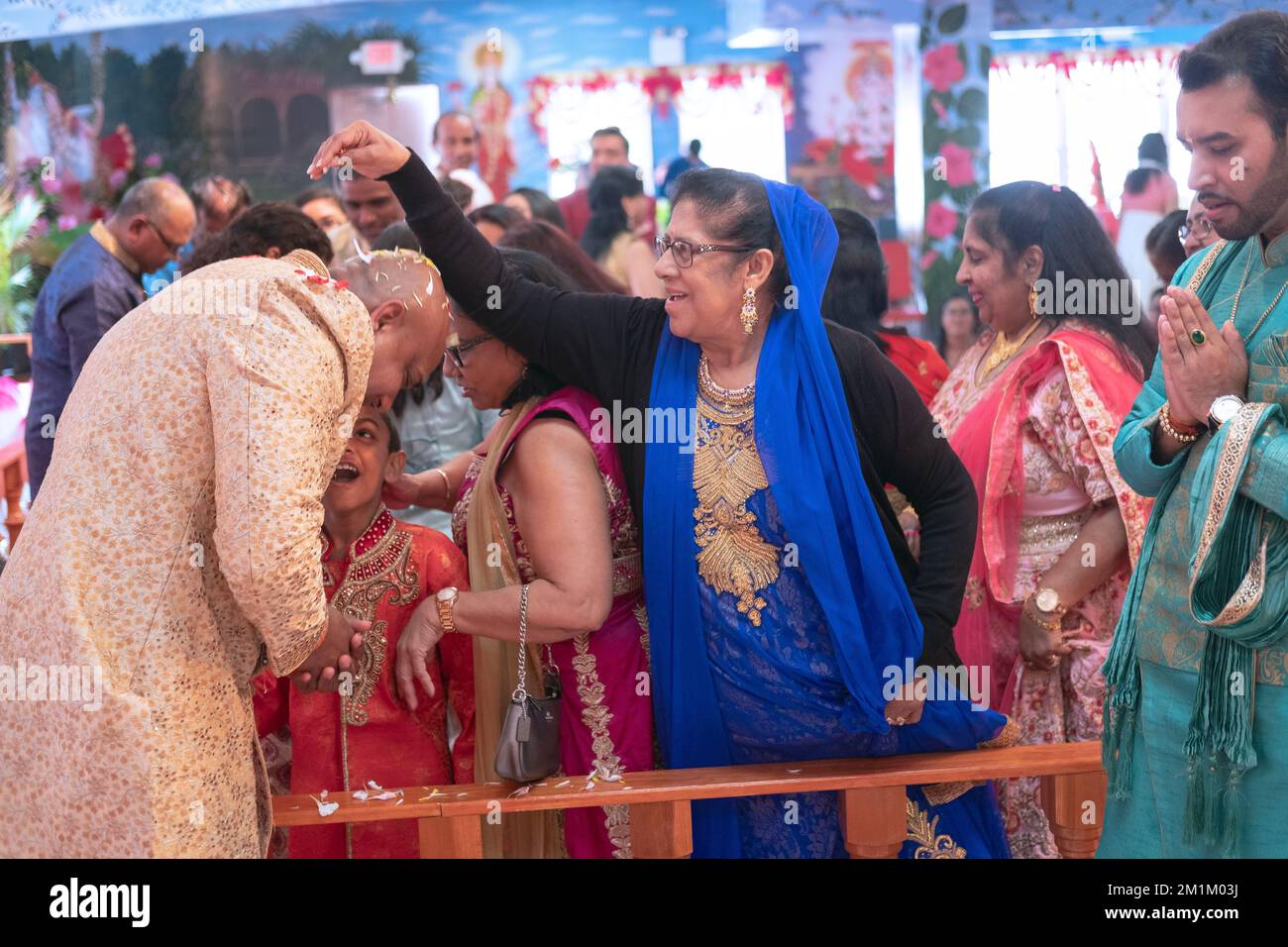 In seinen 50s Jahren streuen Gläubige Blütenblätter auf einen Hindu-Mann, der bei der morgendlichen Gottesdienste in seinem Tempel half, um seinen Geburtstag zu feiern. In Queens, New York City. Stockfoto