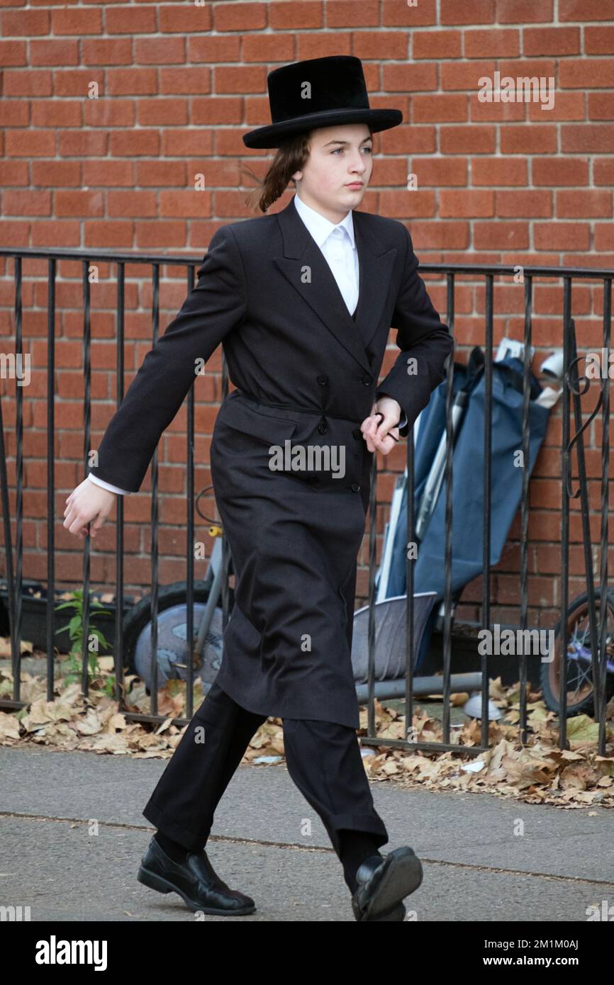 Ein orthodoxer jüdischer junger Mann mit langer Peyot- und schwarzer Kleidung läuft zügig am nördlichen Ende der Lee Avenue in Brooklyn, New York City. Stockfoto