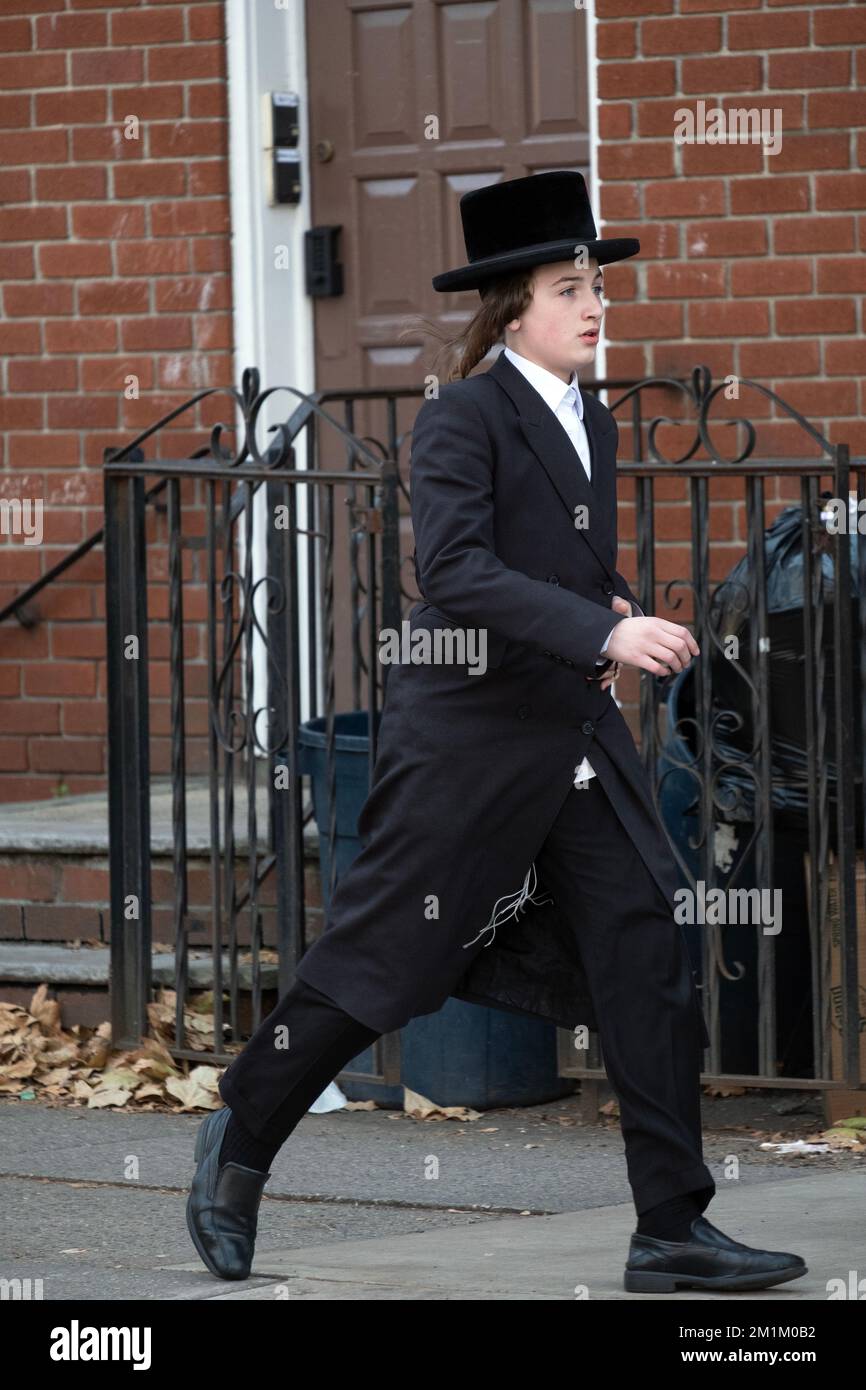 Ein orthodoxer jüdischer junger Mann mit langer Peyot- und schwarzer Kleidung läuft zügig am nördlichen Ende der Lee Avenue in Brooklyn, New York City. Stockfoto