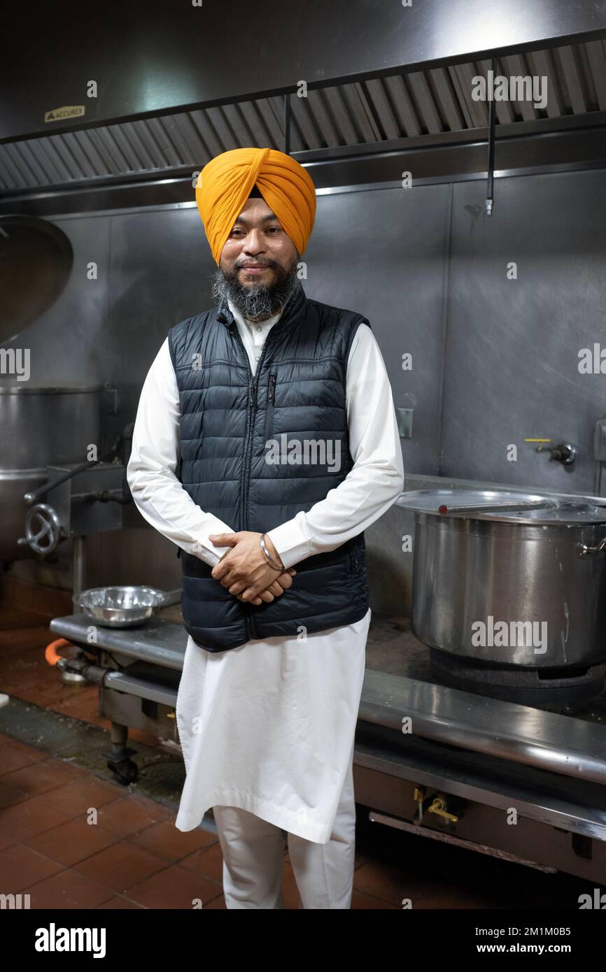 Ein Sikh-Priester, ein Granthi, posiert in der Langar-Küche in einem Tempel in Richmond Hill, Queens, New York City. Stockfoto