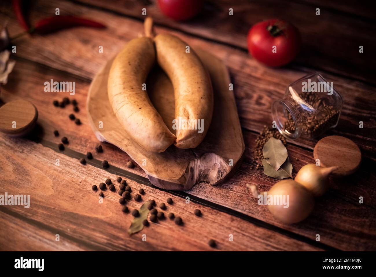 Ein großer Winkel aus geräuchertem Fleisch auf einem Holztisch mit frischen Kräutern und aromatischen Gewürzen Stockfoto