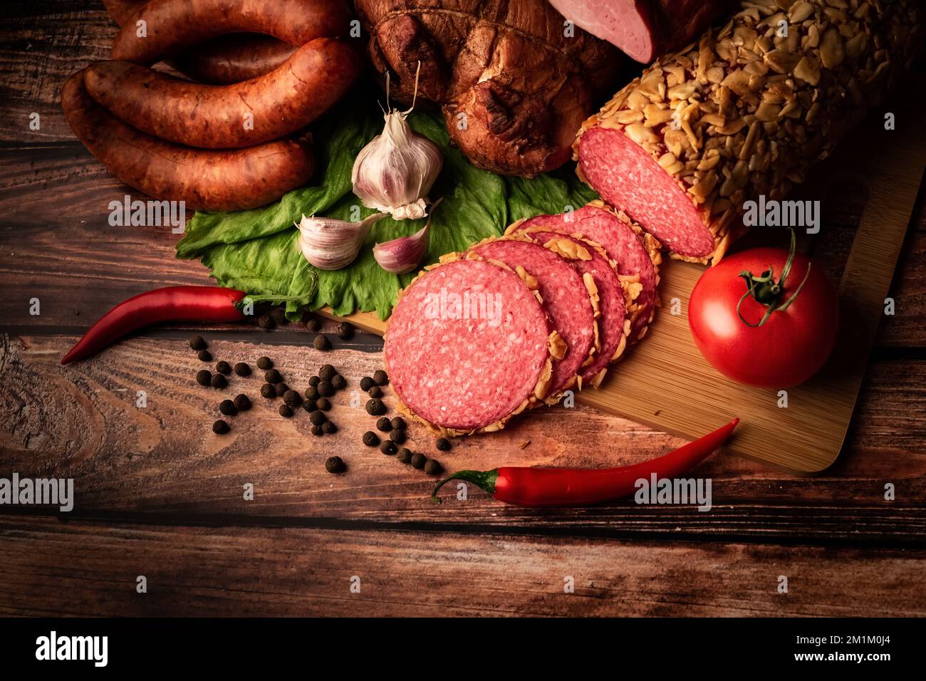 Ein Blick von oben auf geräuchertes Fleisch auf einem Holztisch mit frischen Kräutern und aromatischen Gewürzen Stockfoto