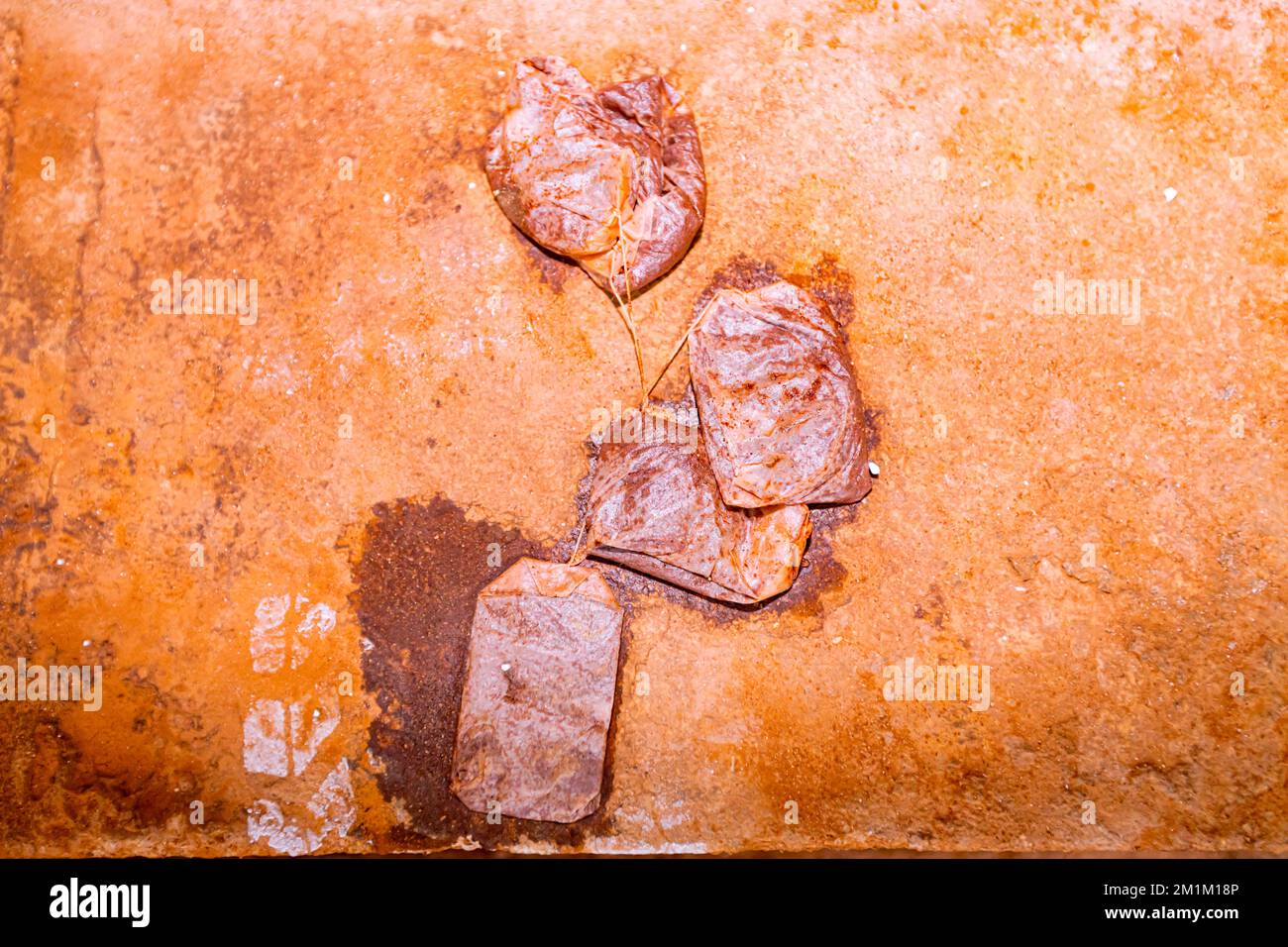Nach der Teezeit warfen die Arbeiter nasse Teebeutel auf die Orange, schmutzig, mit Kaffee verschmiert, Betonboden des Gebäudes im Bau. Stockfoto