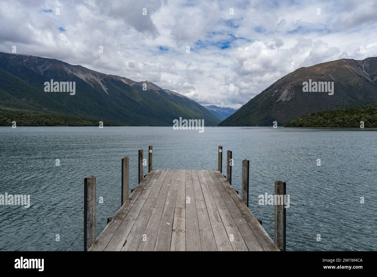 Eine Anlegestelle am Rand eines großen Wasserkörpers mit Bergen im Hintergrund Stockfoto