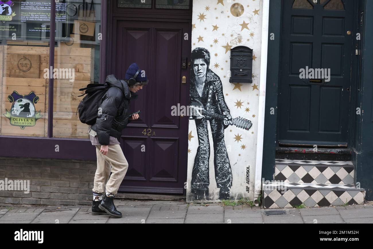 Ein Mann geht an einem Wandgemälde von David Bowie vorbei, gemalt vom Künstler JEF AEROSOL in der Gegend von Brighton, North Laine. Stockfoto