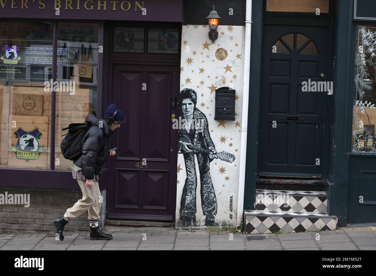 Ein Mann geht an einem Wandgemälde von David Bowie vorbei, gemalt vom Künstler JEF AEROSOL in der Gegend von Brighton, North Laine. Stockfoto