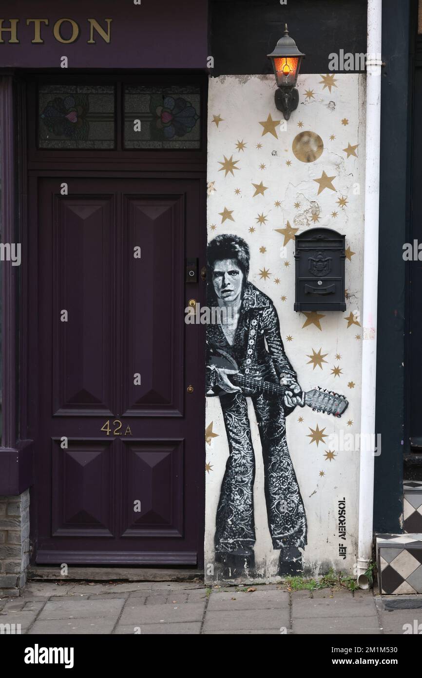 Ein Mann geht an einem Wandgemälde von David Bowie vorbei, gemalt vom Künstler JEF AEROSOL in der Gegend von Brighton, North Laine. Stockfoto