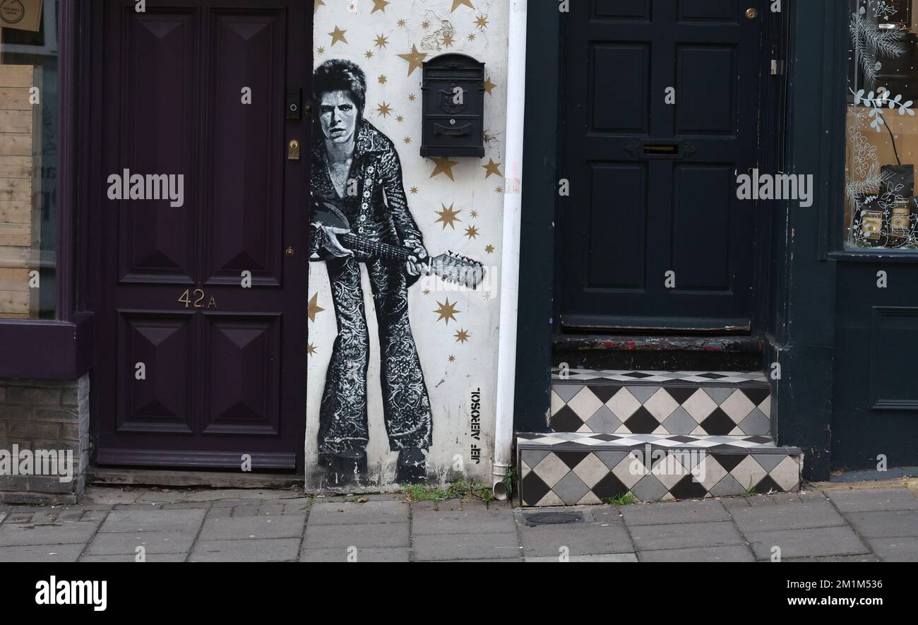 Ein Mann geht an einem Wandgemälde von David Bowie vorbei, gemalt vom Künstler JEF AEROSOL in der Gegend von Brighton, North Laine. Stockfoto