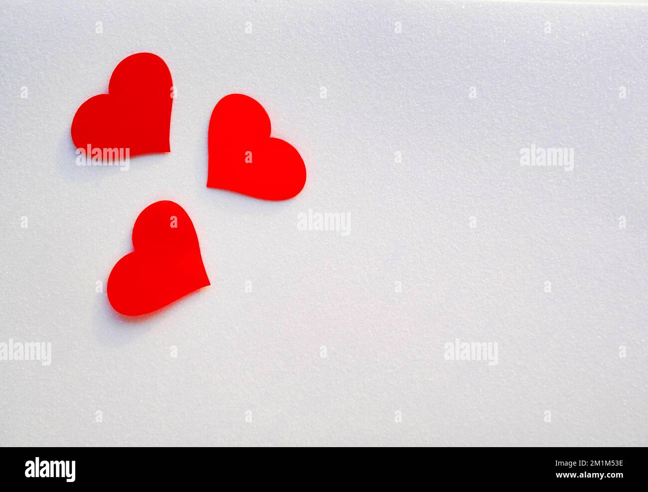 Drei rote, dekorative Herzen auf glitzerndem weißem Hintergrund mit Kopierbereich. Valentinskarte. Stockfoto