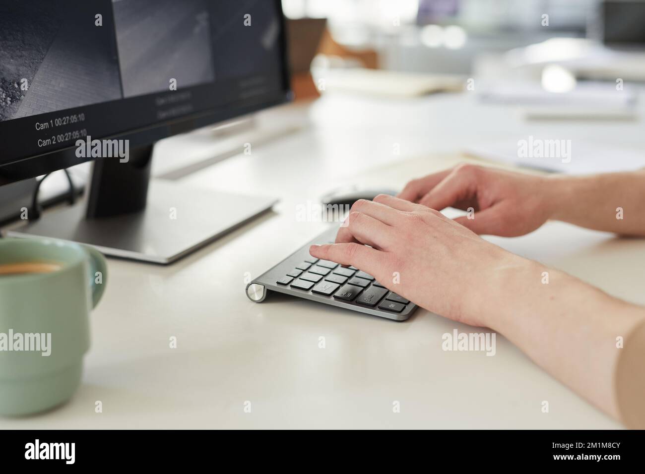 Nahaufnahme einer jungen Frau, die auf der Tastatur tippt, während sie mit Überwachungsmaterial in der Sicherheitszentrale arbeitet Stockfoto