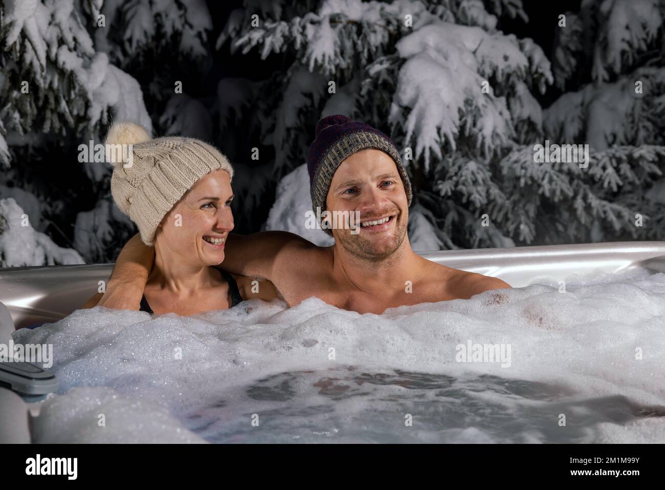 Ein junges Paar, das sich im Winter im Wannen-Whirlpool im Freien entspannen kann Stockfoto