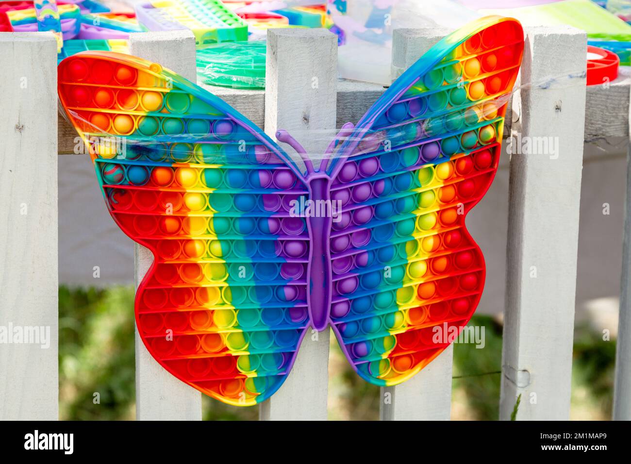 Pop-IT-Spielzeug-Schmetterling auf einem weißen Zaun Stockfoto