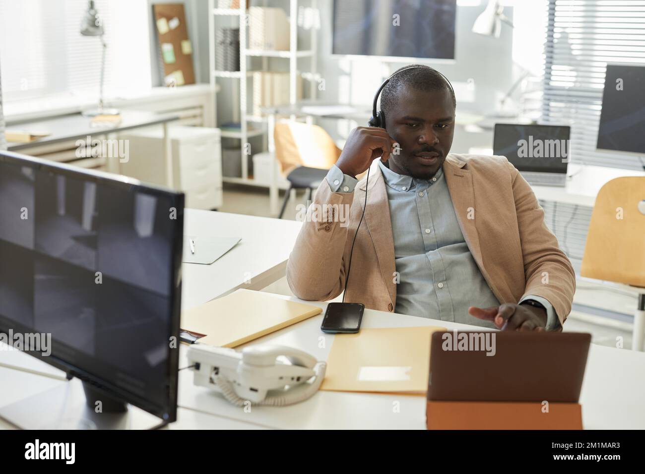 Porträt eines Schwarzen, der über ein Headset spricht und einen beratenden Kunden im Callcenter oder im Büro des technischen Supports berät Stockfoto