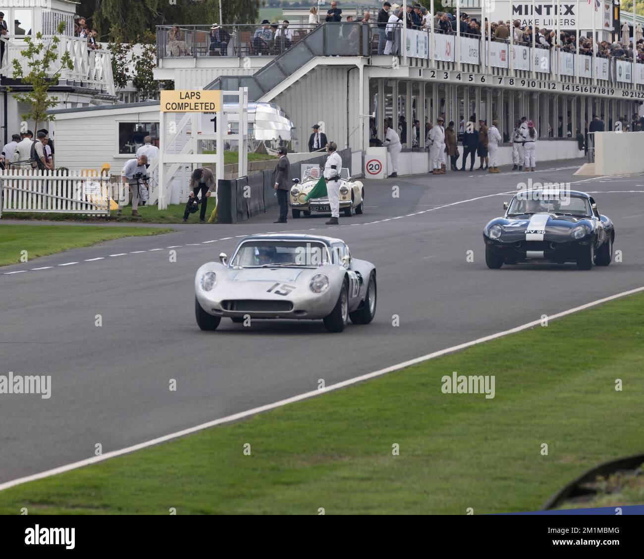 Ein Tojeiro-Ford Sportwagen aus dem Jahr 1962 führt einen Jaguar E-TYPE während der Goodwood Revival 2022 an den Gruben vorbei Stockfoto