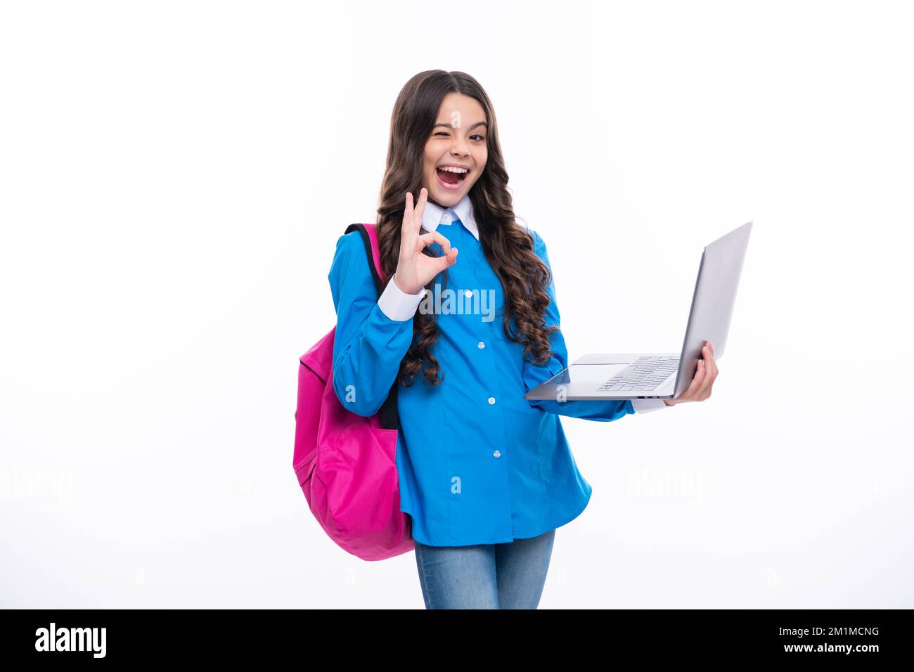 Aufgeregtes Gesicht. Schulmädchen in Schuluniform mit Laptop. Schulkind, Teenager-Student mit weißem isoliertem Hintergrund. Erstaunlicher Ausdruck, fröhlich und froh. Stockfoto