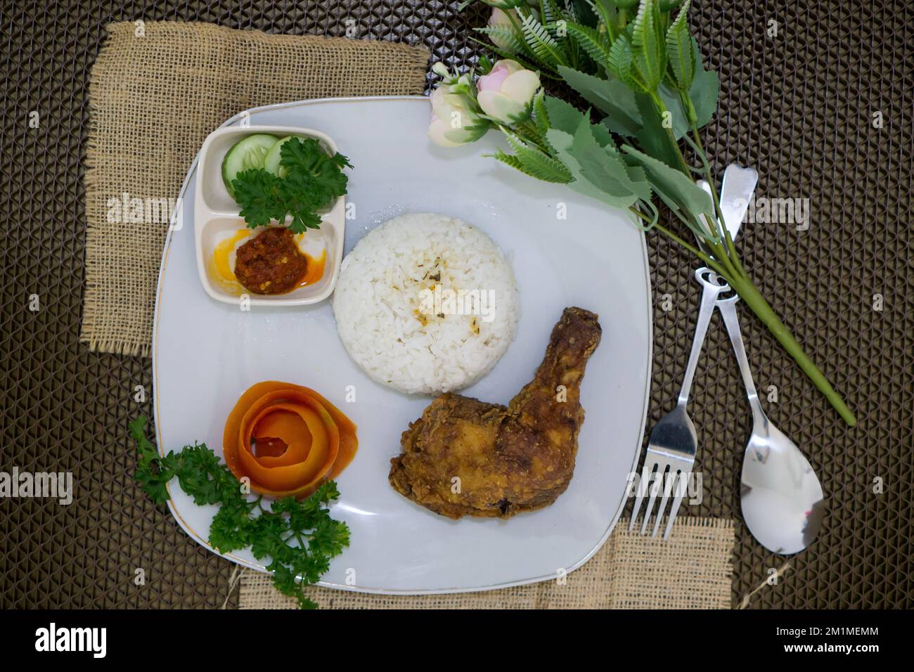 Hausgemachtes indonesisches Essen, Hähnchenbutter mit weißem Reis, Gemüse, Tomaten und Chilisauce Stockfoto